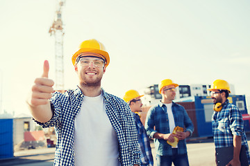 Image showing group of smiling builders in hardhats outdoors