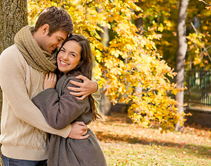 Image showing smiling couple hugging over autumn background