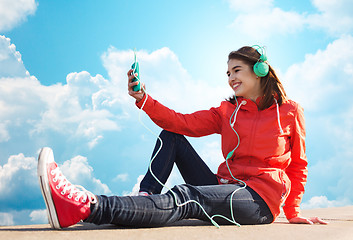 Image showing happy young woman with smartphone and headphones