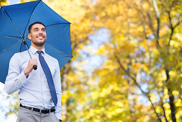 Image showing businessman with umbrella over autumn background