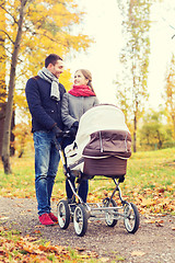 Image showing smiling couple with baby pram in autumn park