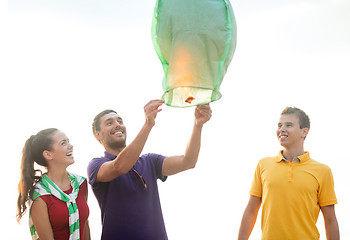 Image showing happy friends with chinese sky lantern on beach