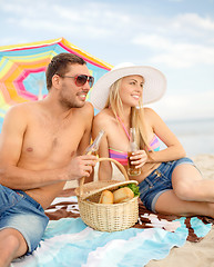 Image showing happy couple having picnic and sunbathing on beach