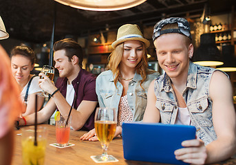 Image showing happy friends with tablet pc and drinks at bar