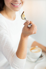 Image showing close up of woman eating cake at cafe or home