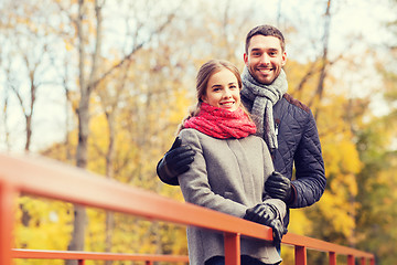 Image showing smiling couple hugging on bridge in autumn park