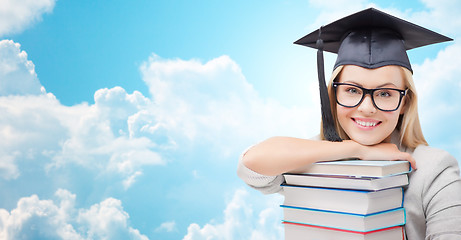 Image showing student in trencher cap with books over blue sky