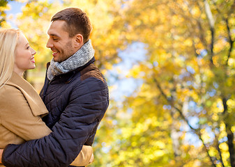 Image showing smiling couple hugging over autumn background