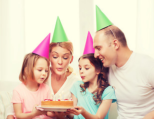 Image showing smiling family with two kids in hats with cake