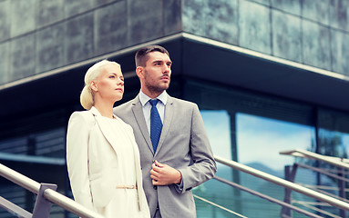 Image showing serious businessmen standing over office building