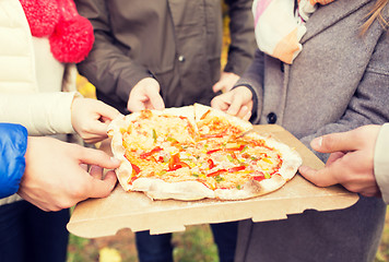 Image showing close up of friends hands eating pizza outdoors