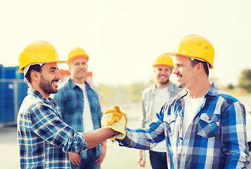 Image showing group of smiling builders shaking hands outdoors