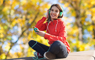 Image showing happy young woman with smartphone and headphones