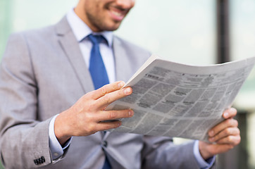 Image showing close up of smiling businessman reading newspaper