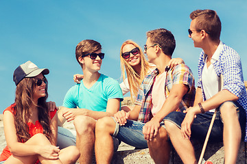 Image showing group of smiling friends sitting on city street