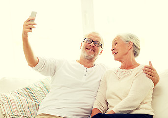 Image showing happy senior couple with smartphone at home