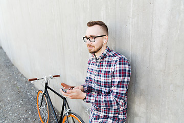 Image showing hipster man in earphones with smartphone and bike