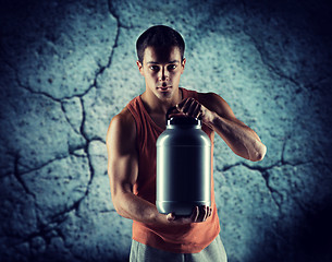 Image showing young male bodybuilder holding jar with protein