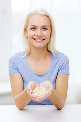 Image showing happy woman holding pills or capsules at home