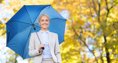 Image showing businesswoman with umbrella over autumn background