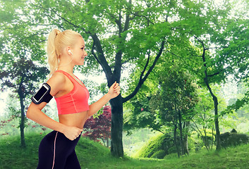 Image showing sporty woman running with smartphone and earphones