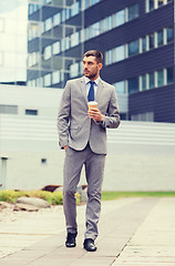 Image showing young serious businessman with paper cup outdoors