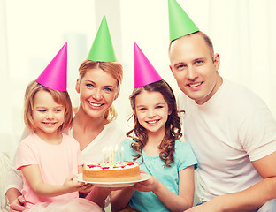 Image showing smiling family with two kids in hats with cake