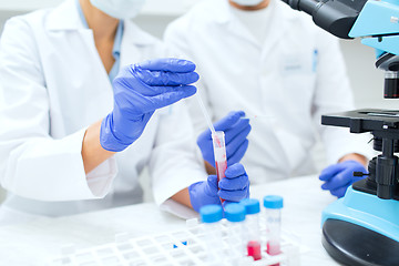 Image showing close up of scientists filling test tube in lab