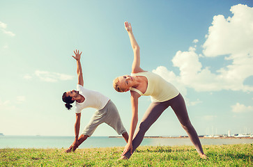 Image showing smiling couple making yoga exercises outdoors