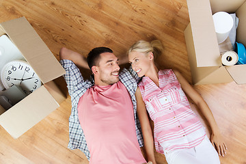 Image showing happy couple lying on floor among cardboard boxes