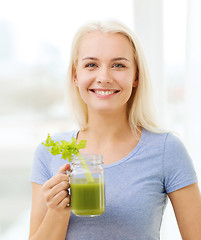 Image showing smiling woman drinking juice or shake at home