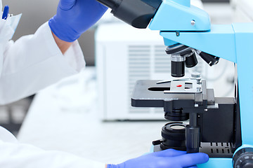 Image showing close up of hands with microscope and blood sample