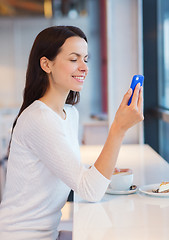 Image showing smiling woman with smartphone and coffee at cafe