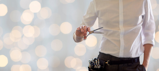 Image showing close up of male stylist with scissors over lights