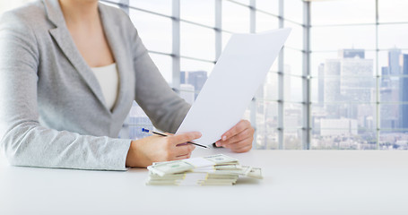 Image showing close up of female hands with money and tax report