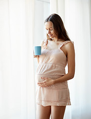 Image showing happy pregnant woman with cup drinking tea at home