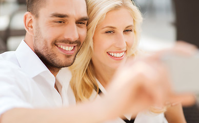 Image showing happy couple taking selfie with smatphone outdoors