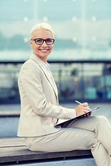 Image showing young smiling businesswoman with notepad outdoors