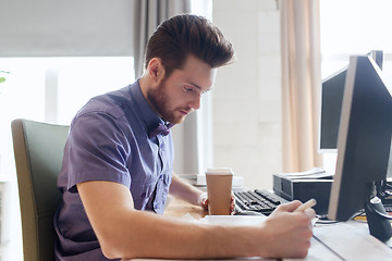 Image showing creative male office worker with coffee writing