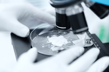 Image showing close up of hand with microscope and powder sample