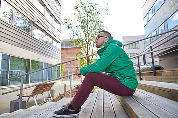 Image showing happy young hipster man sitting on stairs in city