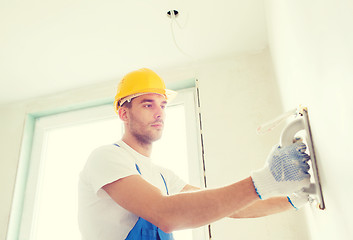 Image showing builder with grinding tool indoors