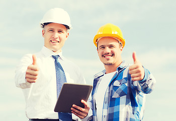 Image showing smiling builders in hardhats with tablet pc