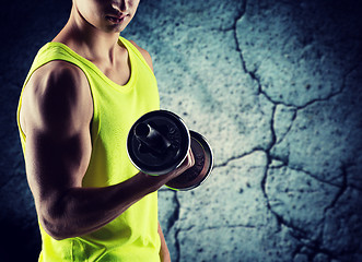 Image showing close up of young man with dumbbell flexing biceps