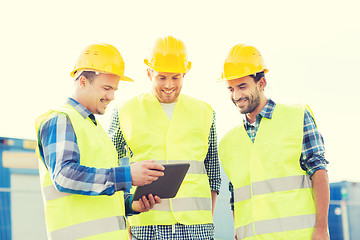 Image showing smiling builders in hardhats with tablet pc