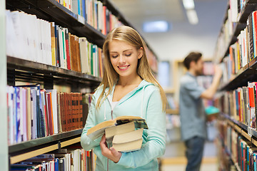 Image showing happy student girl or woman with book in library