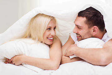 Image showing happy couple lying in bed and talking at home