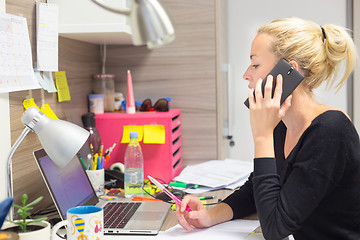 Image showing Businesswoman talking on mobile phone in office.