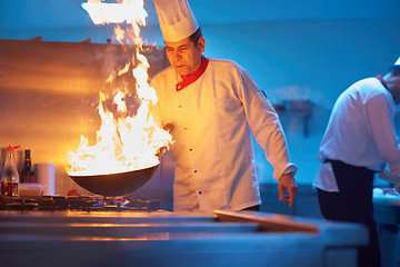 Image showing chef in hotel kitchen prepare food with fire