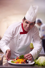 Image showing chef in hotel kitchen preparing and decorating food